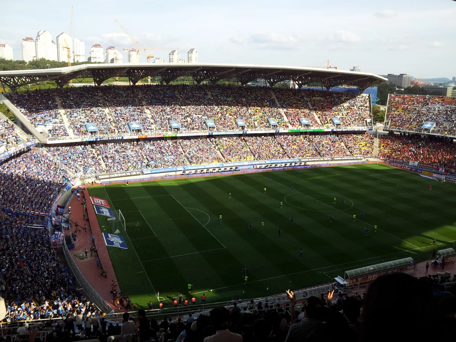 A Super Match at Suwon World Cup Stadium, the home stands in blue and the away section in red behind a banner